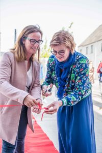 Trui Tydgat van Matexi (links) en burgemeester Tania De Jonge (rechts) openen de kijkwoning in woonbuurt Populierenhof