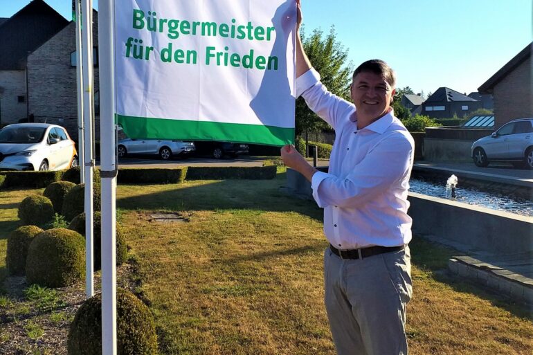 Burgemeester Soetens met vlag voor gemeentehuis Lierde