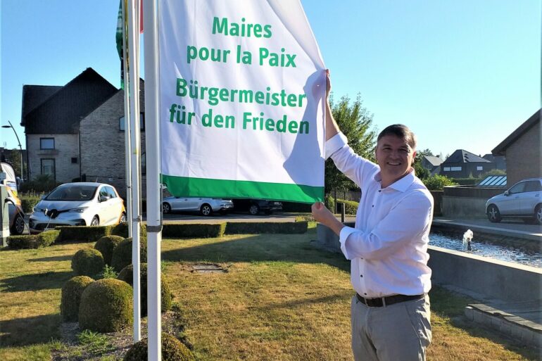 Burgemeester Soetens met vlag voor gemeentehuis Lierde